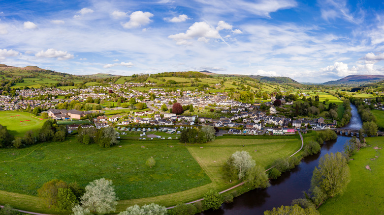 An aerial view of a river, fields, and Crickhowell town in Wales, with hills on the horizon