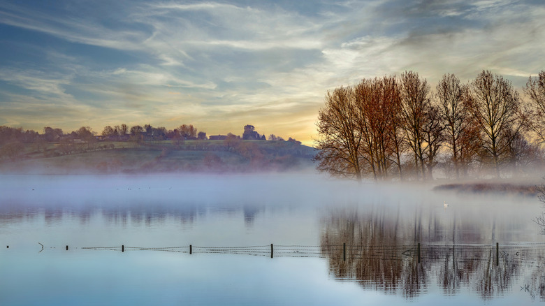 Mist laying atop the water and a view across Rutland Water towards Hambleton, UK at dusk