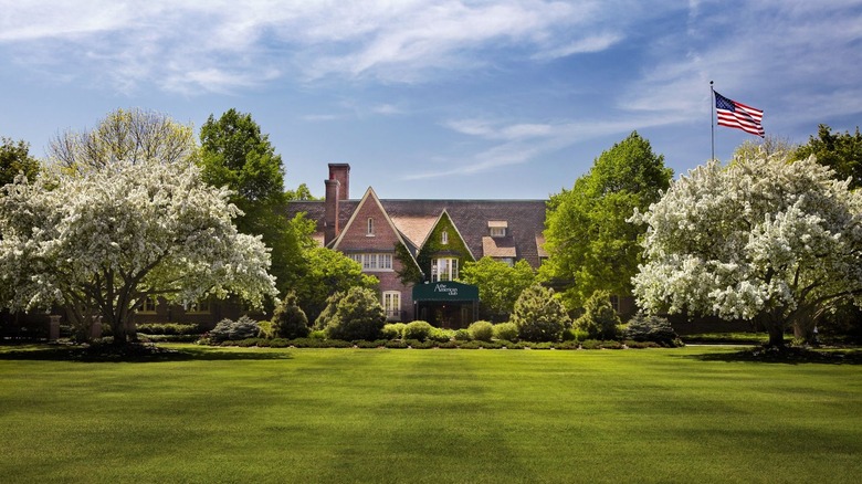 The entrance to the American Club Resort with towering trees on either side