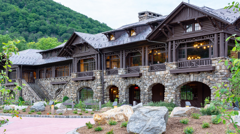 View of the rustic Bear Mountain Inn in New York during the day with trees and a mountain side in the background.