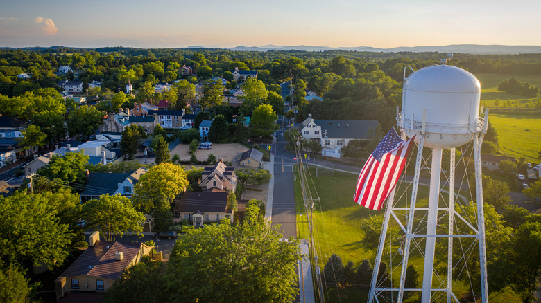An aerial view of a town amidst trees, a water tower, and rolling hills
