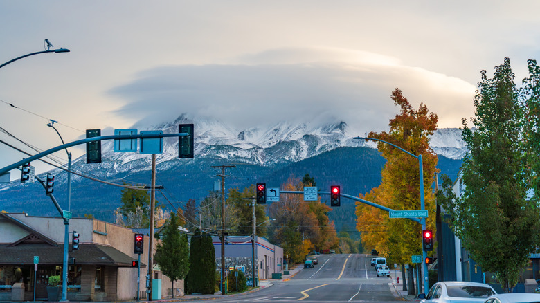 An intersection in Mount Shasta City, with Mount Shasta visible beneath clouds in the background