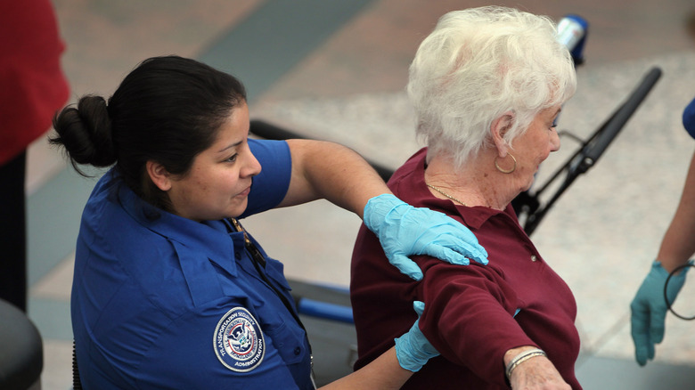 A female traveler receives a pat-down from a female TSA agent.