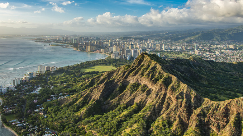 The city of Oahu next to a towering mountain and the blue ocean