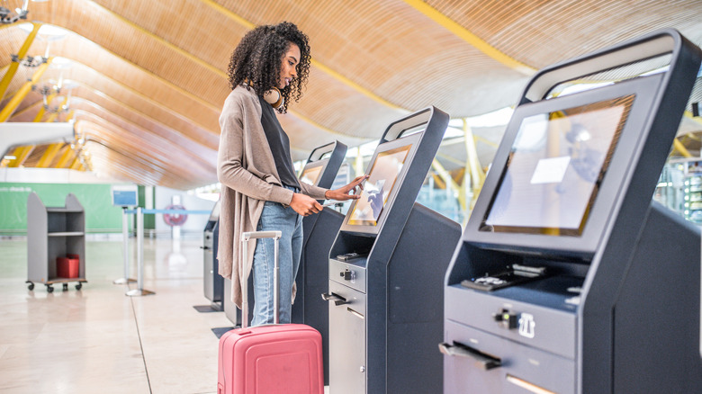 A woman checking in for her flight at an airport kiosk