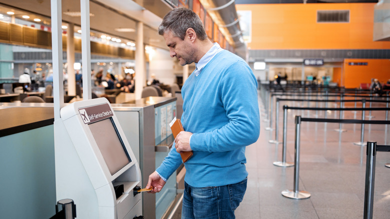 A man paying at an airport kiosk