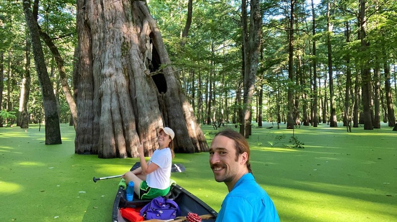 A smiling man and woman pose for a picture while canoeing through a cypress stand at Sky Lake, in Mississippi.