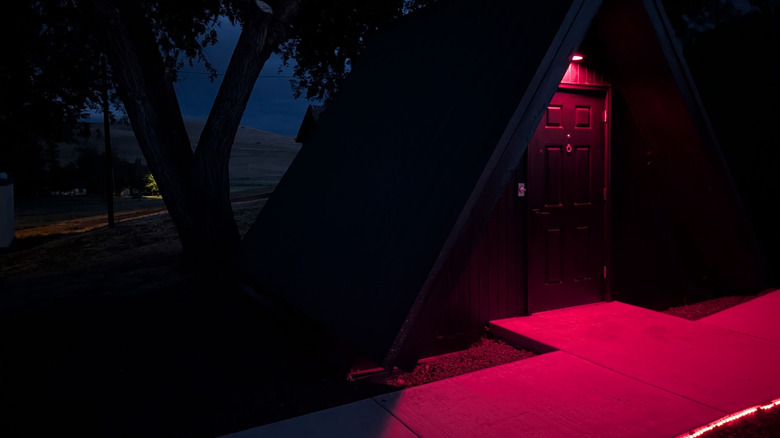 View of A-frame cabin exterior at Antelope Base Camp lit with red lights at night