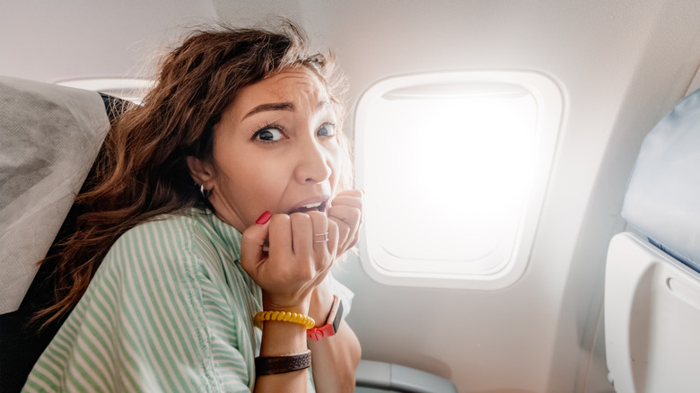 A close-up of a woman experiencing anxiety while on a plane