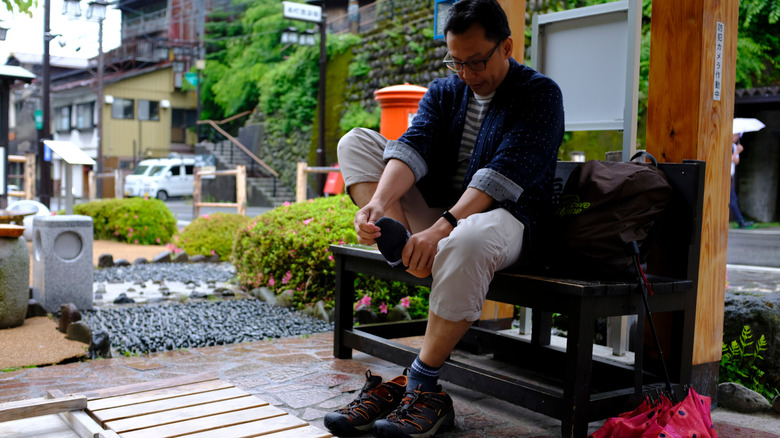Man removing his shoes at the entrance of a hot spring.