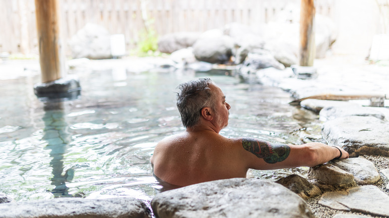 A foreigner in a hot spring in Japan with a tattoo.