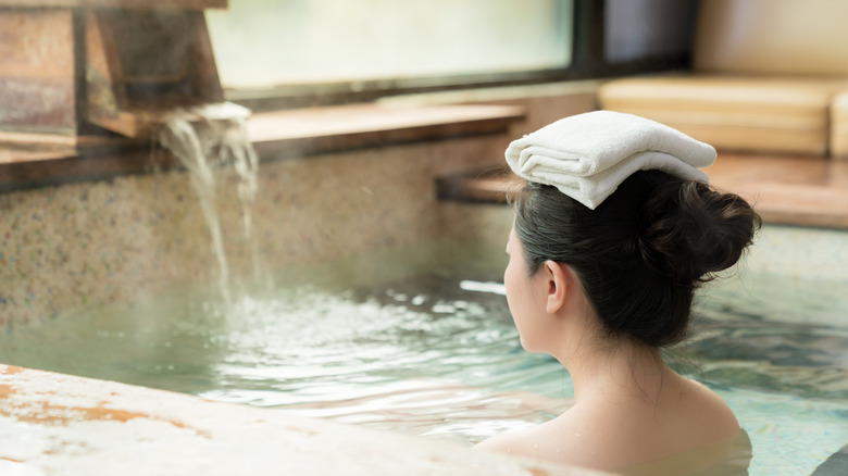 Woman with towel on her head sitting in the hot spring.