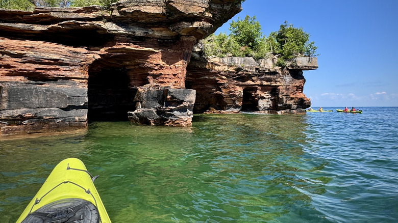 People exploring the Apostle Islands sea caves in kayaks on a sunny day