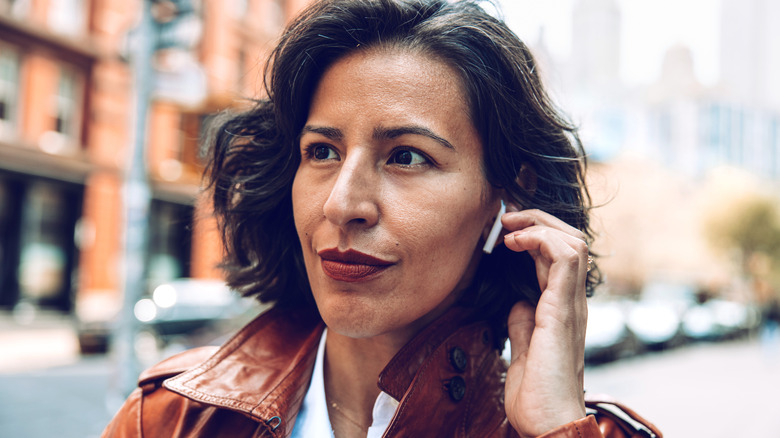 A woman walking down the street with AirPods in her ears