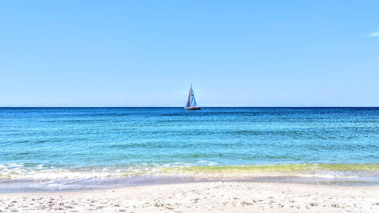 Ship sailing on a blue ocean before white sands at Aqualane Shores, Florida, on a clear day