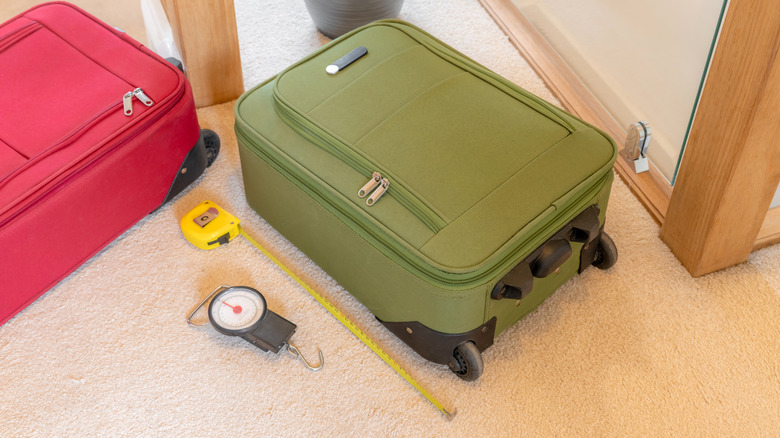 A carry-on bag next to a tape measure and a luggage scale