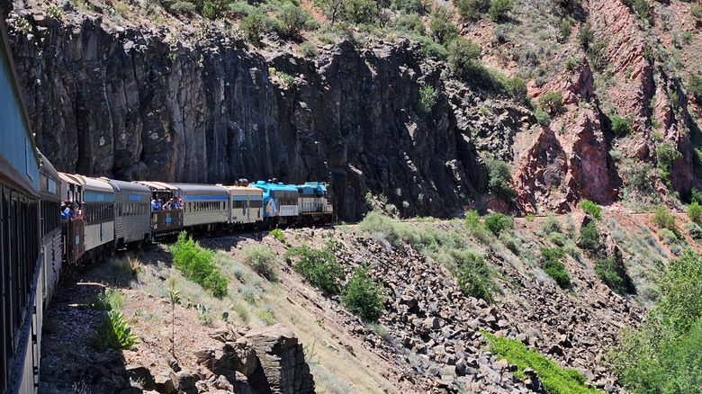 A train riding alongside steep cliffs in the western U.S.