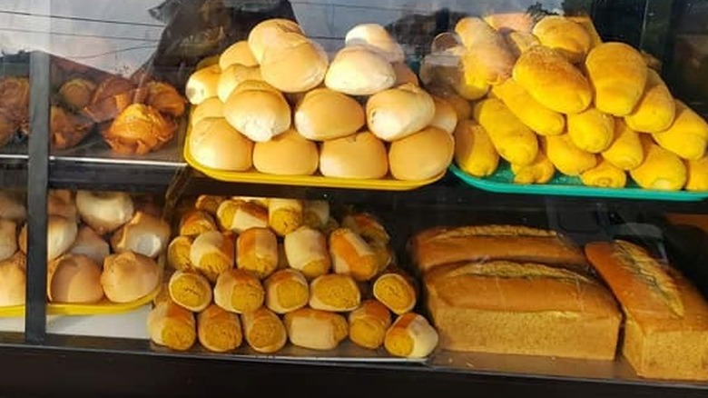 A display case with bread and rolls on trays at Barrio Bakery