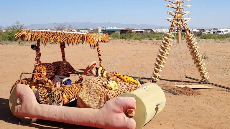 An art installation of a Flinstones car sitting on desert sand at Saguaro Man in Arizona