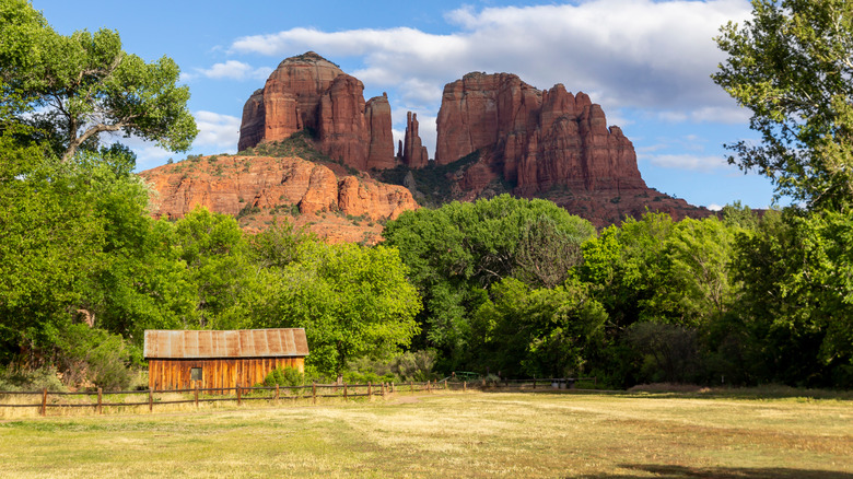 Small cabin surrounded by trees and a wooden fence, standing at the foot of Cathedral Rock in Arizona