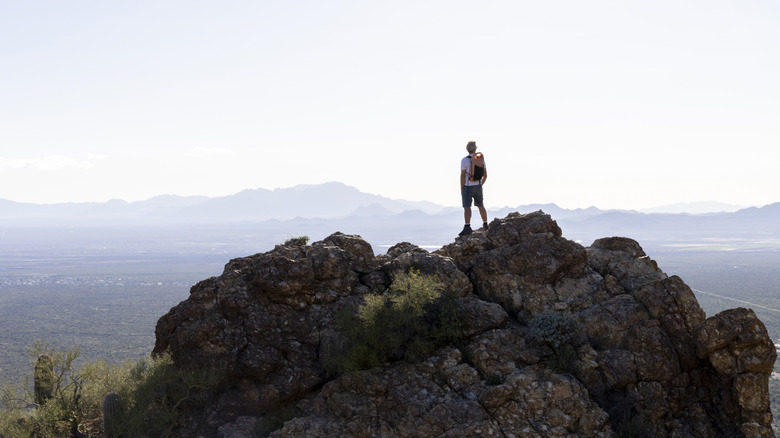 Man takes in view on mountain while hiking near Tucson, Arizona