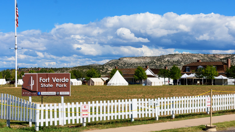 Fort Verde State Park sign with buildings in the background