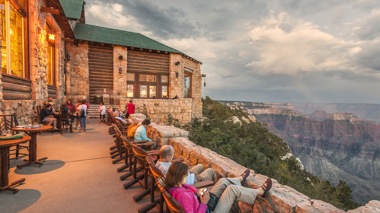 Guests of the former Grand Canyon Lodge lounge on Adirondack chairs on the terrace overlooking an epic view of the North Rim