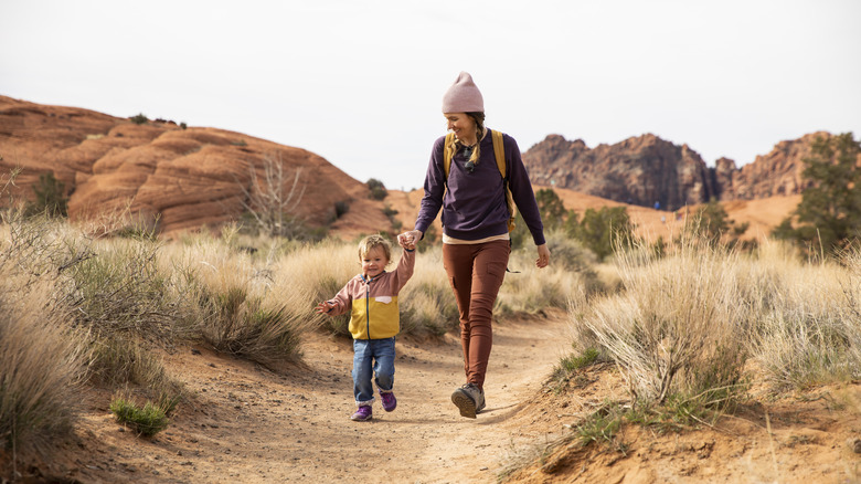 Woman and young boy hold hands on hiking trail
