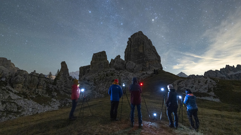 Five people with cameras stargazing in front of large rocks