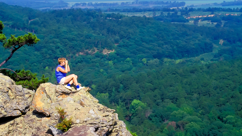 A person sitting on rocks looking over a bluff