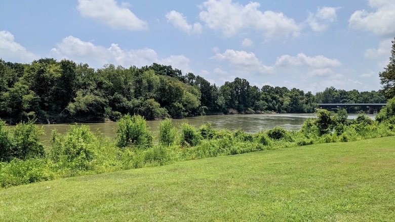 View of the Black River in Arkansas, surrounded by green trees, grassy banks, and a bridge in the distance