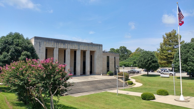 Old Randolph County Courthouse in Pocahontas, Arkansas, with stone columns, entrance steps, flowering trees, and flags