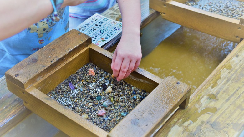 A child sifts through a sluice for colorful gems