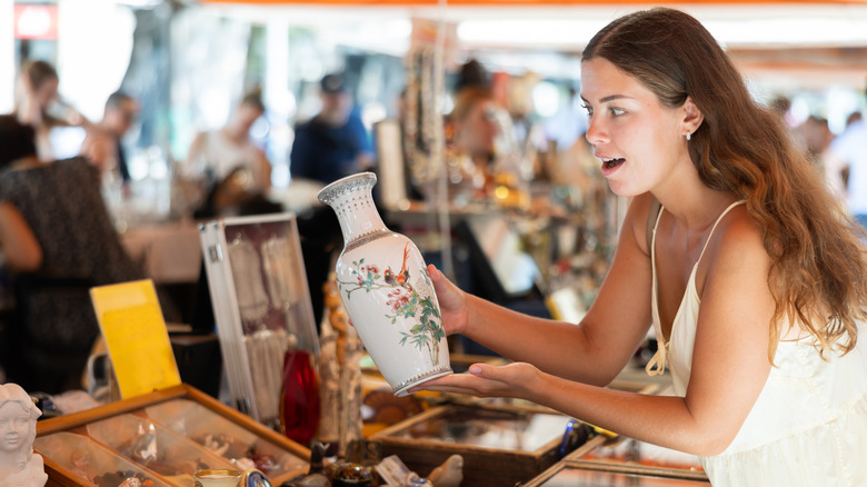 Woman holding a ceramic vase at a flea market