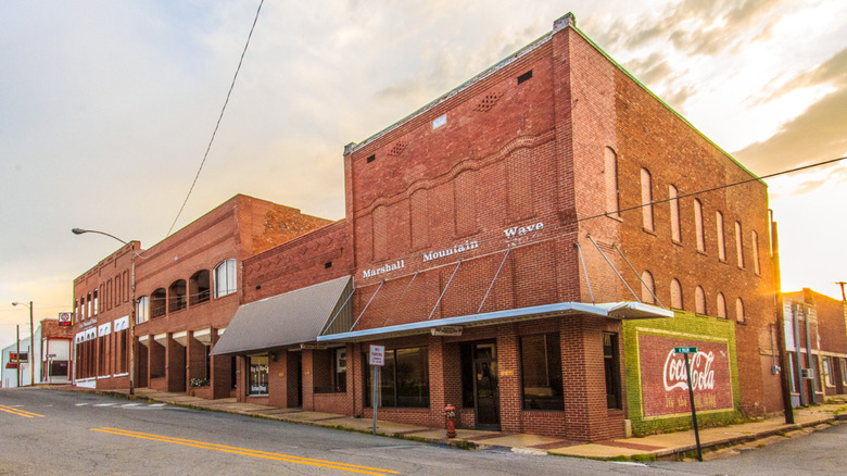 red brick building on black empty street under sunrise