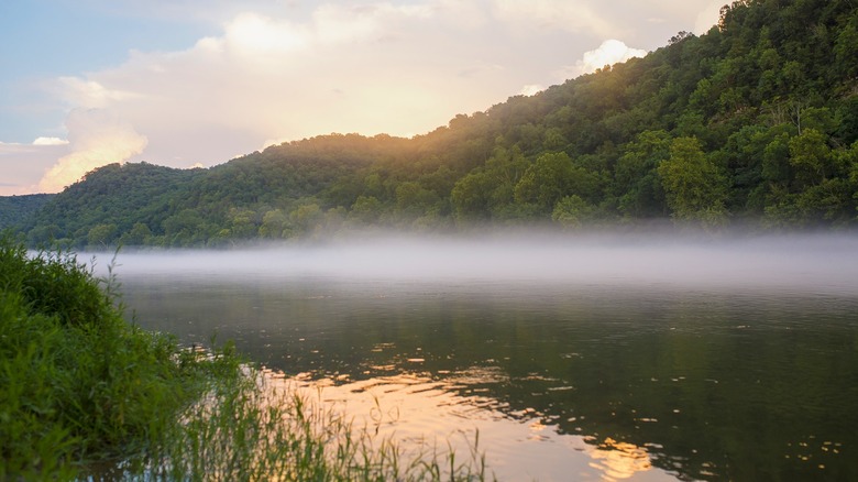 A layer of fog sits over the White River in Arkansas as sun rises behind the ridge.