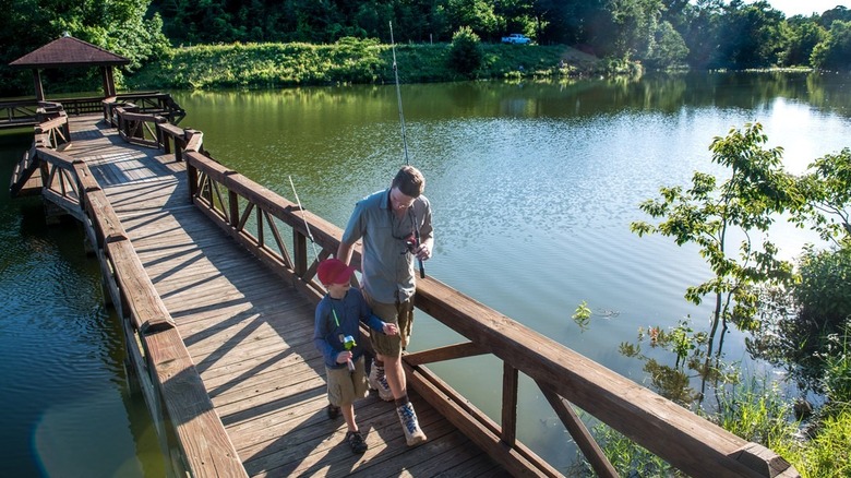 Man and son walking on fishing pier with fishing poles, Woolly Hollow State Park