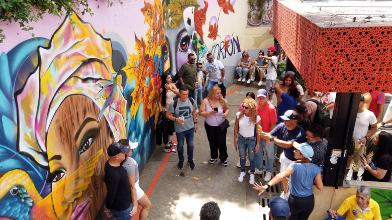People taking pictures in front of colorful street art in Comuna 13