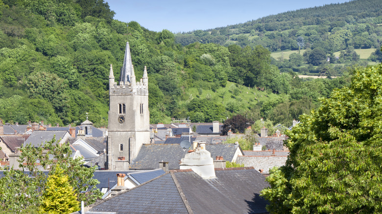 A church steeple and rooftops surrounded by forest in the Devonshire town of Ashburton, England