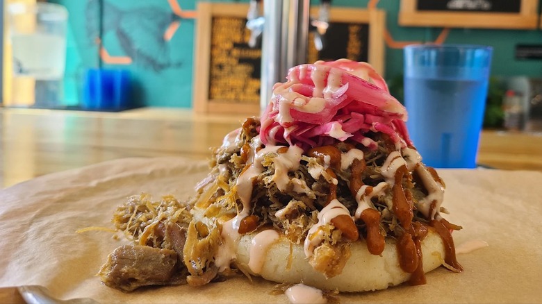 The pernil arepa topped with shredded pork shoulder and pink pickled onions at Little Chango in Asheville, North Carolina