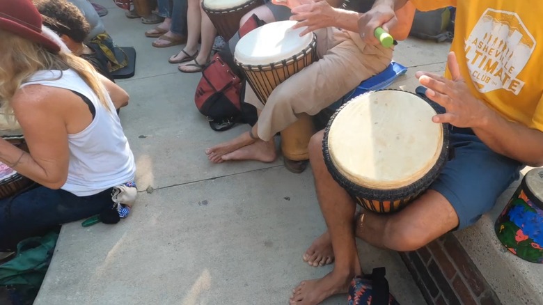 People playing hand drums in Pritchard Park during Asheville Drum Circle