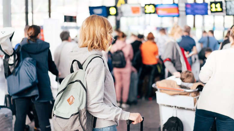 Person waiting in line with backpack and luggage at airport