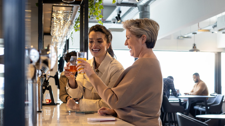 Two female travelers enjoying drinks at an airport bar