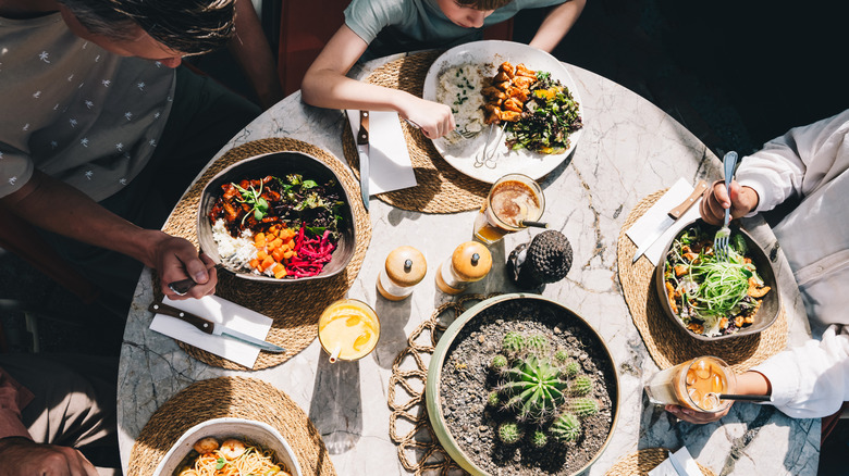 A group of friends gather around the table of food