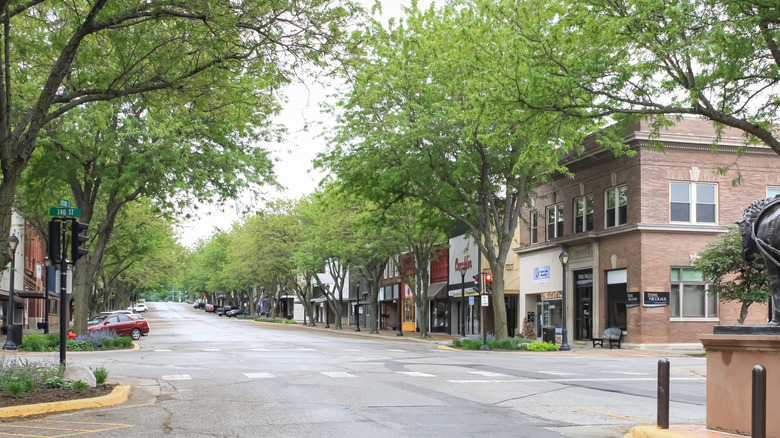 Quiet street lined with trees and local shops on bright day in downtown Atlantic, Iowa
