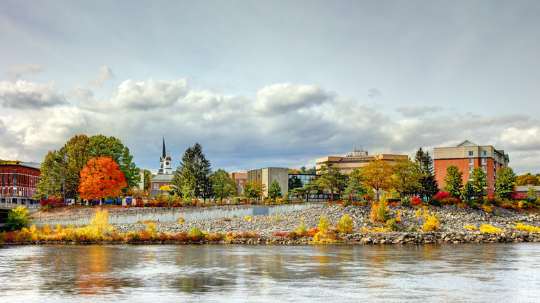A view of buildings in Auburn, Maine, from the Androscoggin River on a cloudy day in autumn.