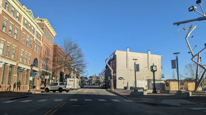 A view of a street lined with cars and buildings on a clear, bright day in Auburn, Maine