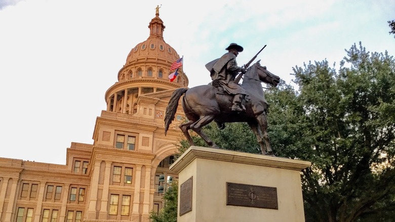 tree and statue of a man on horseback in front of Texas' Capitol building in Austin