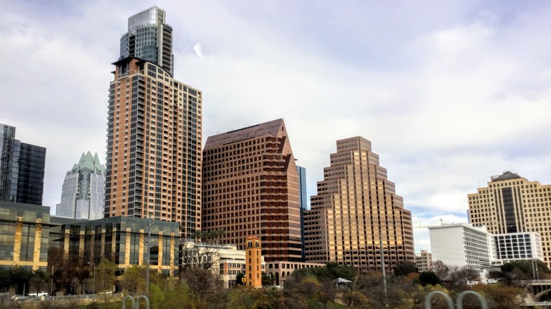 brown, gold, and silver buildings in Austin against a light blue sky with clouds