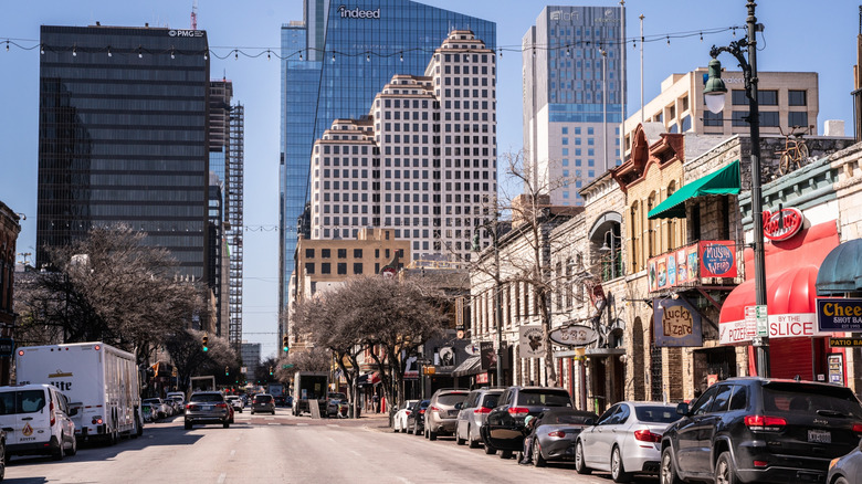 Austin street view with row of buildings and cars, skyscrapers in the background, blue sky